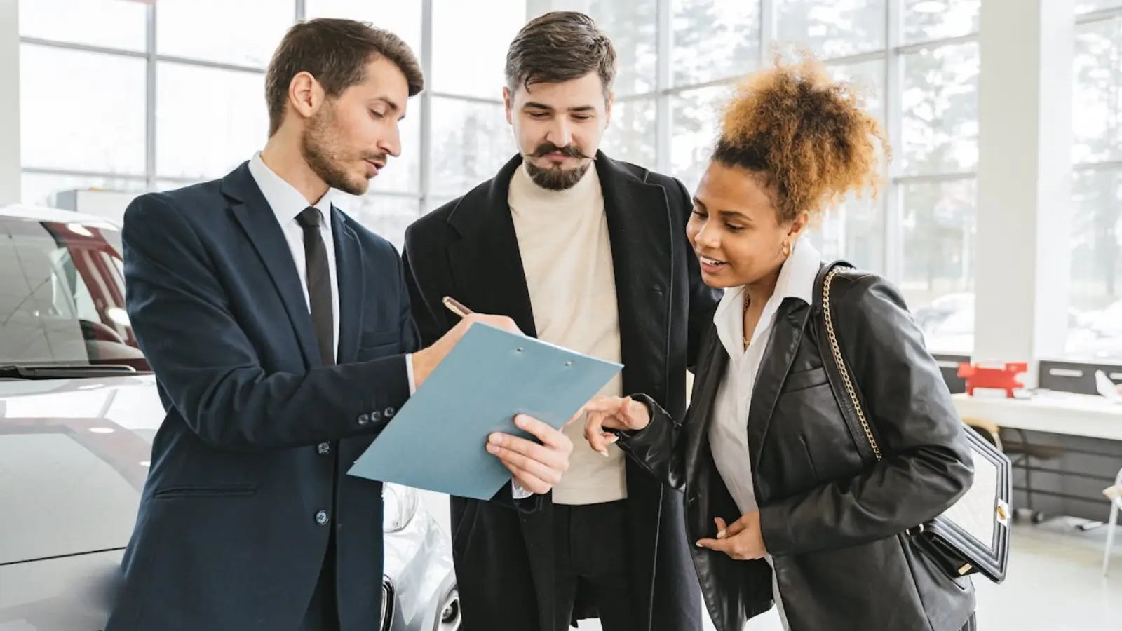 Car broker assisting a client with paperwork at a dealership