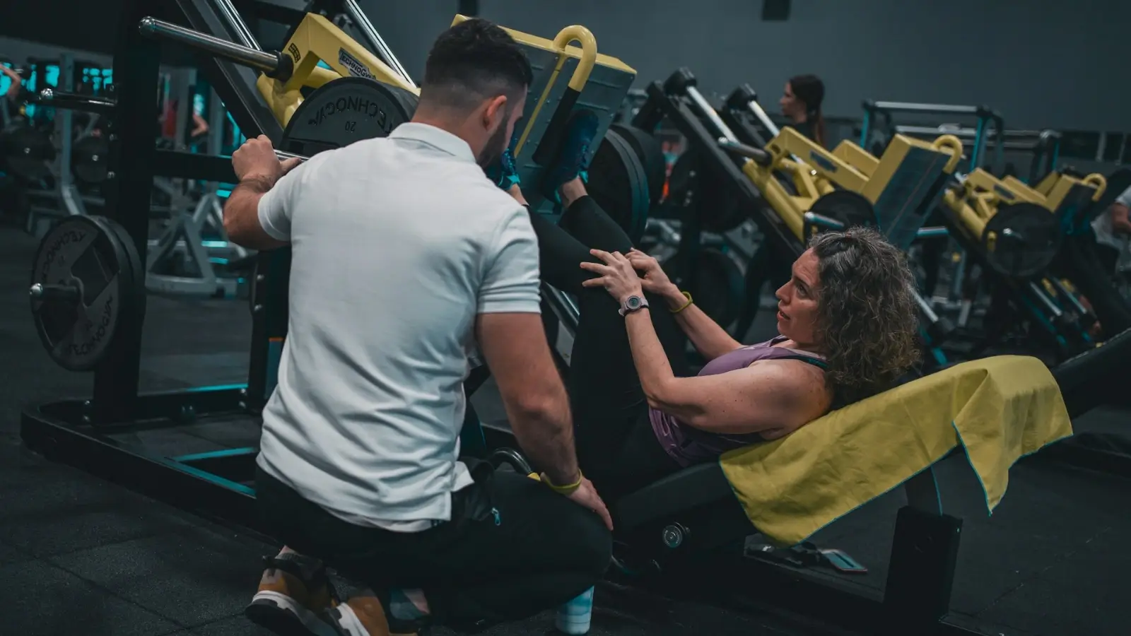 Top Certified Fitness Trainer Courses for Aspiring Fitness Professionals Certified fitness trainer coaching a client in a modern gym environment