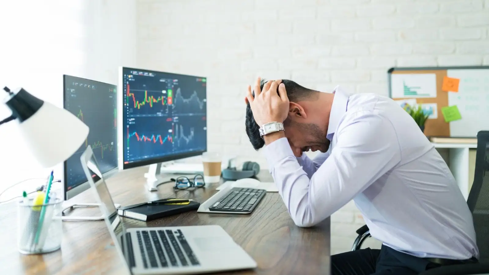 Frustrated beginner trader looking at stock charts on laptop