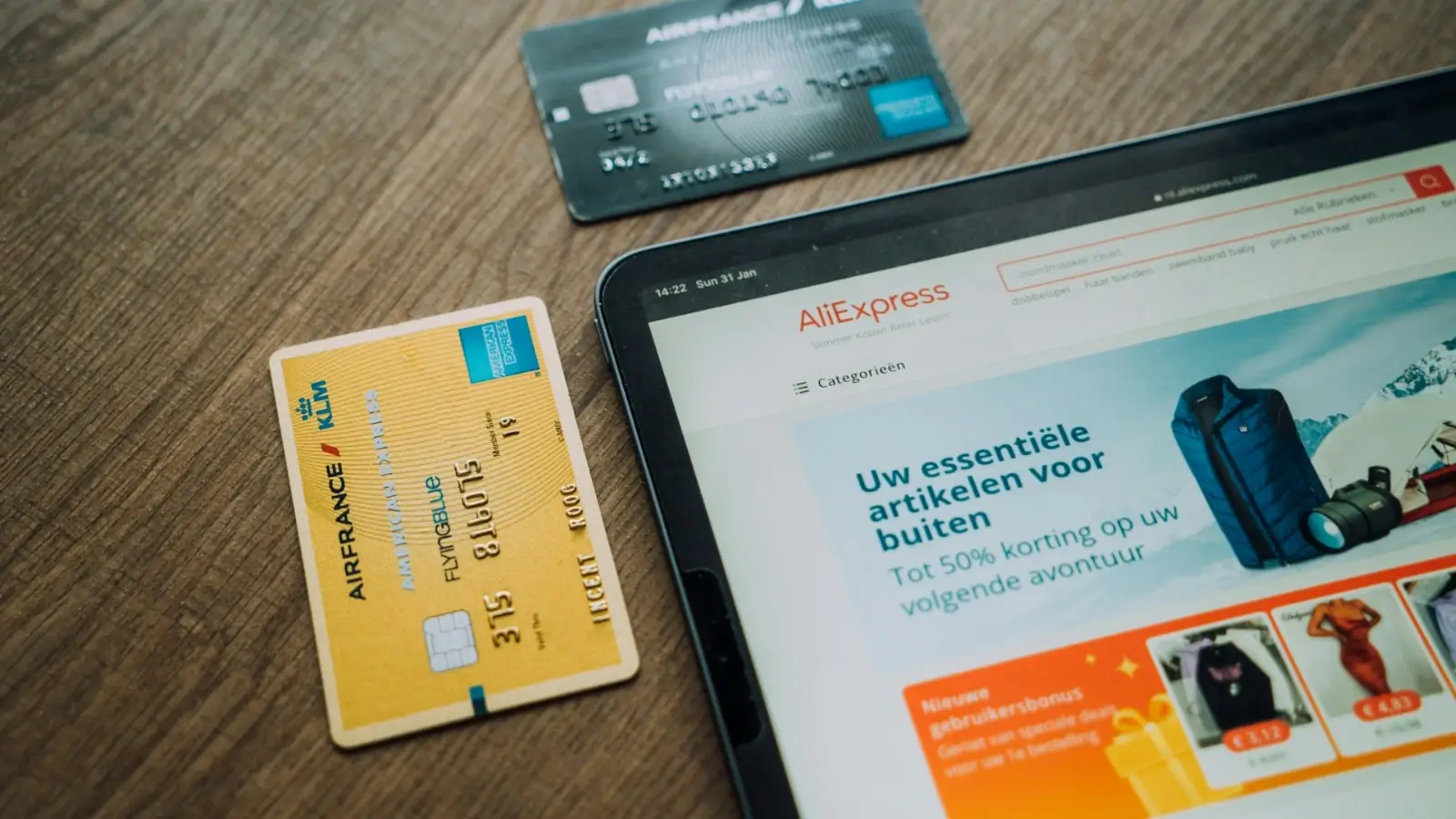 Person shopping online for gadgets and gifts on a tablet with a credit card in hand