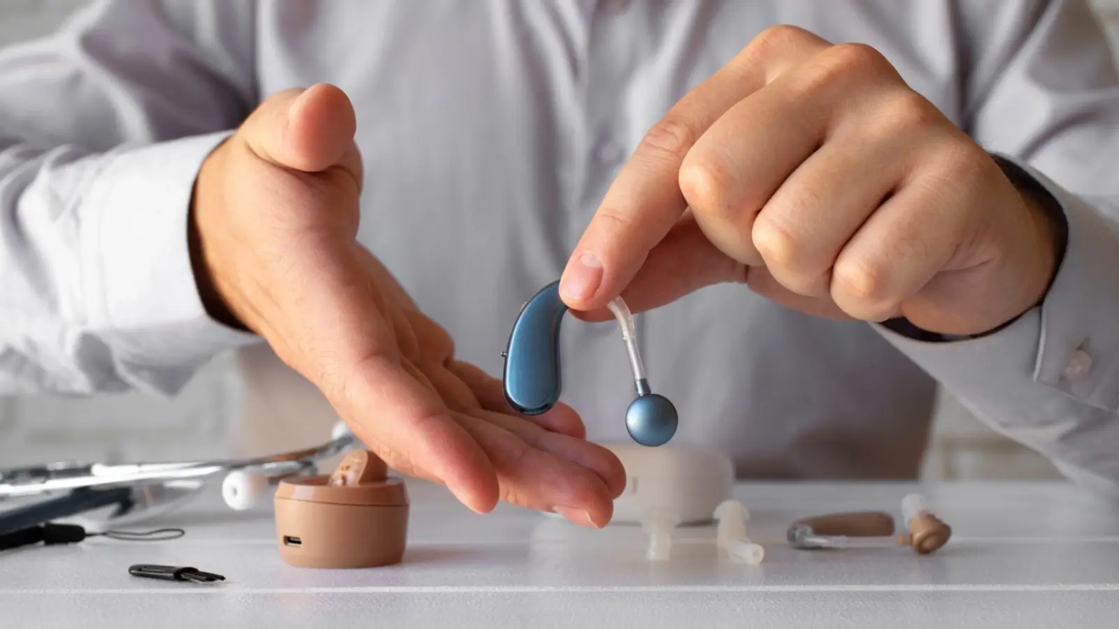 Person testing a behind-the-ear hearing aid with an audiologist