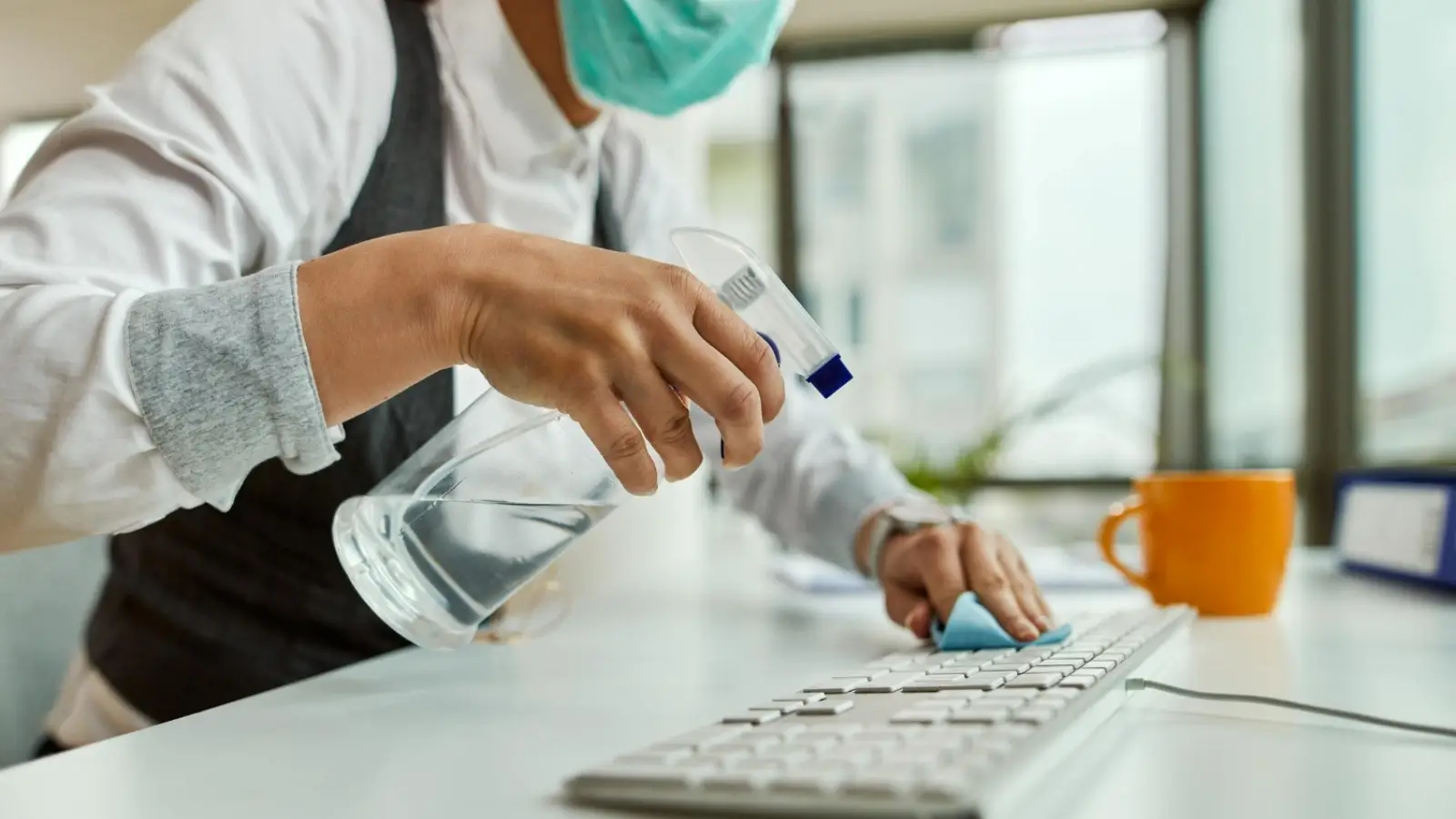 Professional cleaner disinfecting a modern office desk with high-touch surfaces