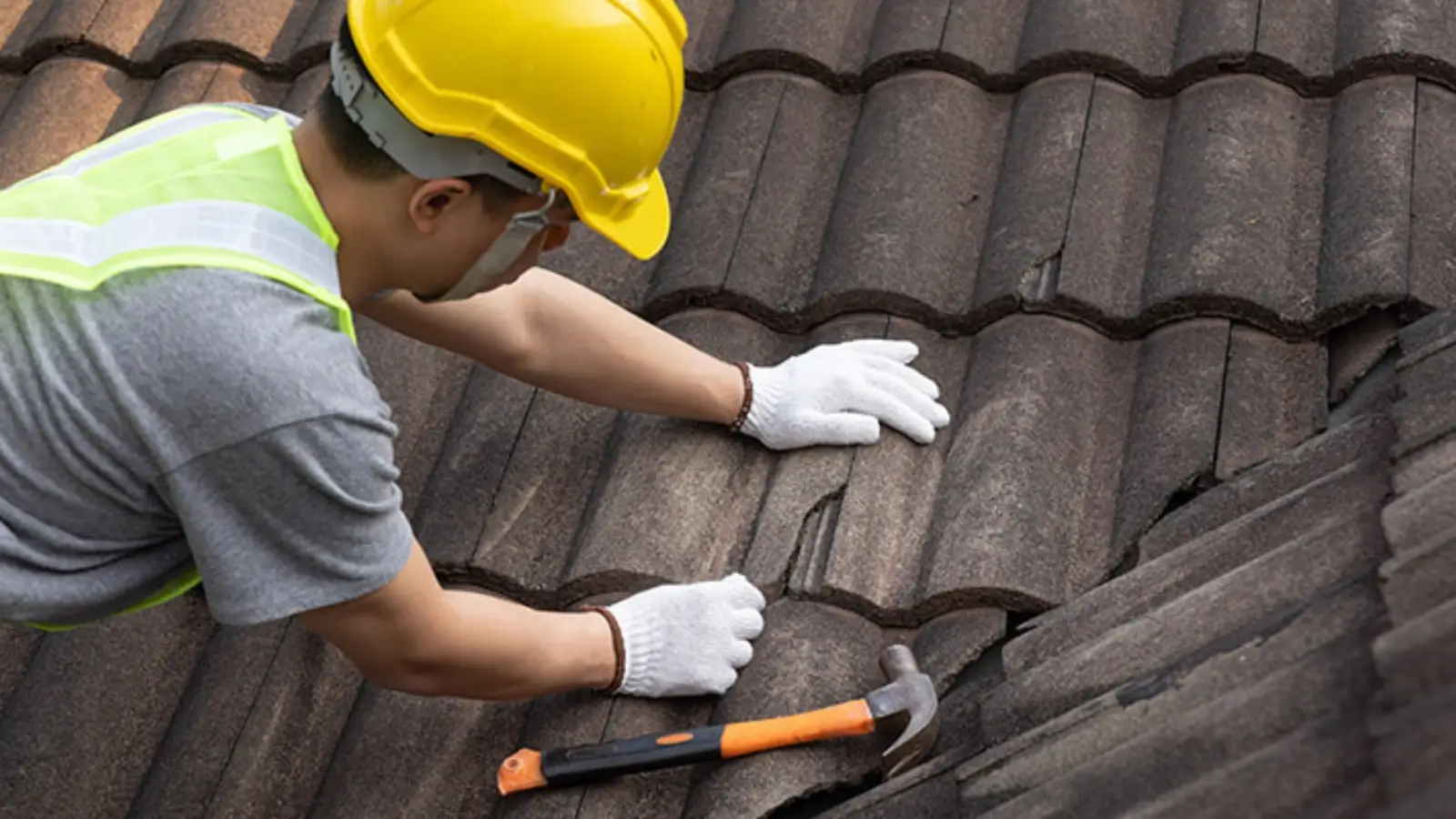 Professional roofer repairing shingles and sealing roof joints on a residential home
