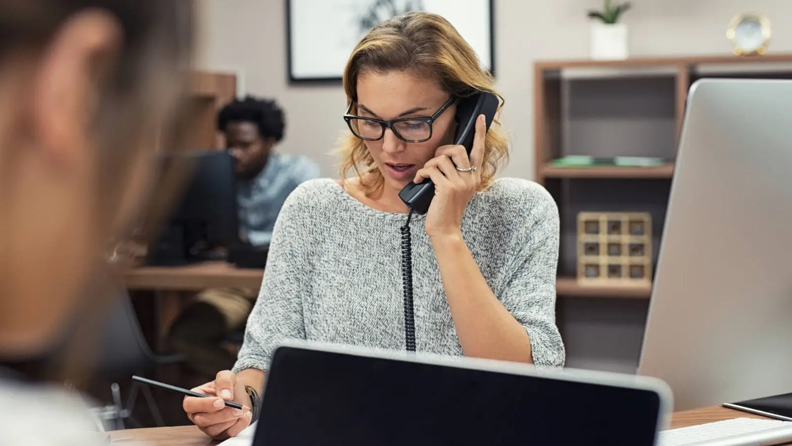 Business owner using a cloud phone system on a laptop and mobile device in modern office