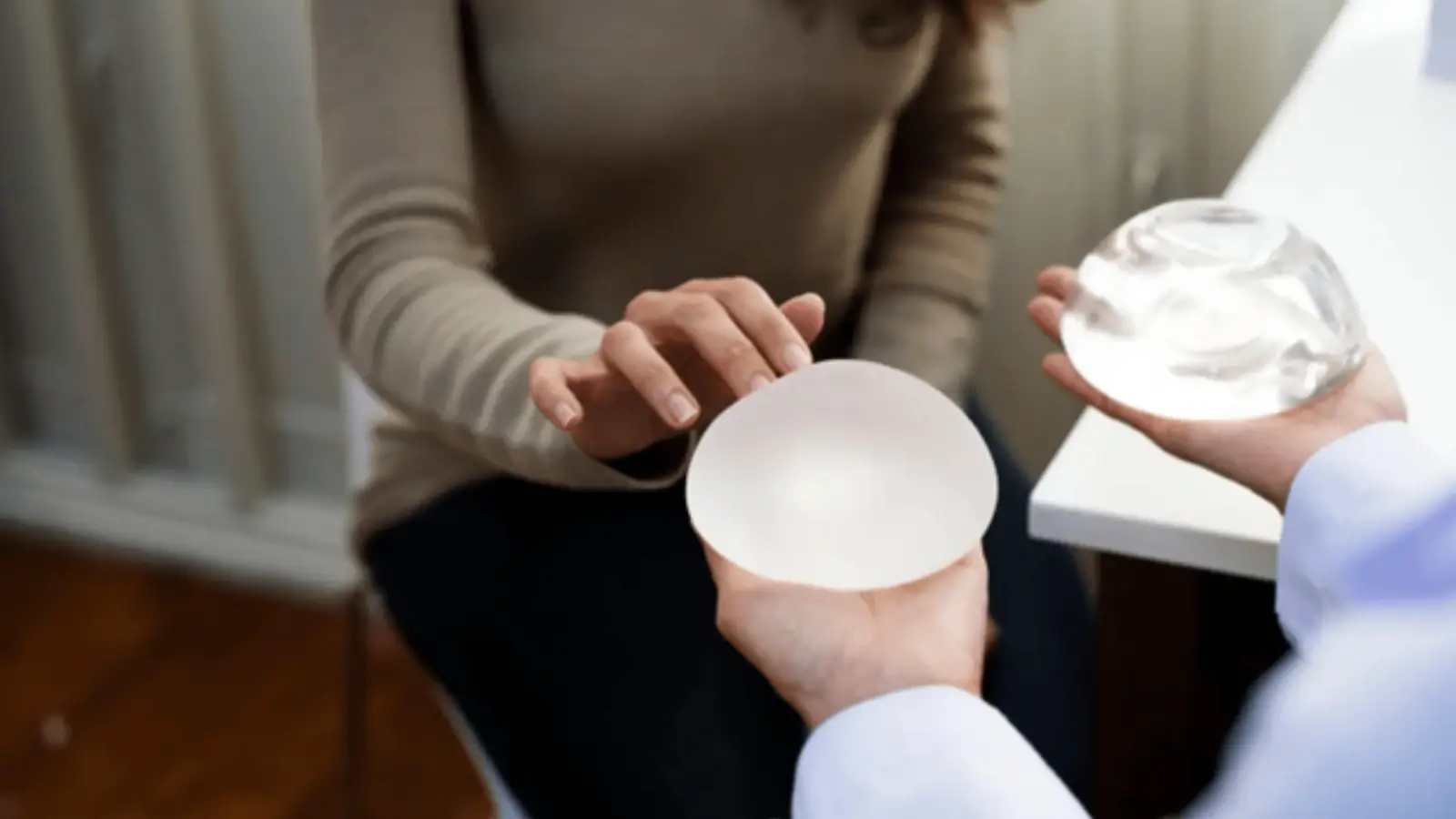 What Type of Implants Are Used in Breast Augmentation? Surgeon showing breast implant options to patient during cosmetic consultation