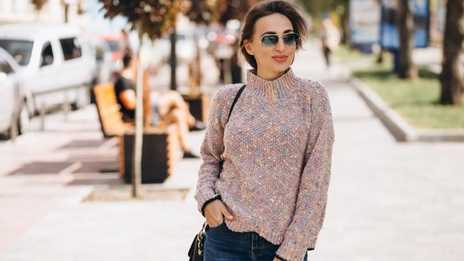 How to Style Women’s Knitwear for Every Occasion Woman wearing a stylish knitted sweater paired with trousers on a city street