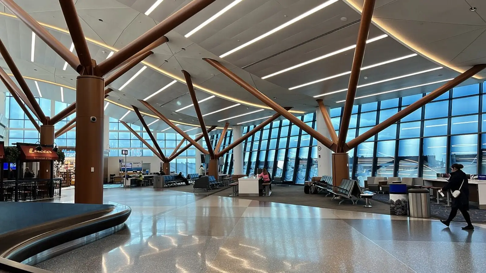 Chauffeur waiting at Boston Logan Airport limo pickup zone with traffic in background