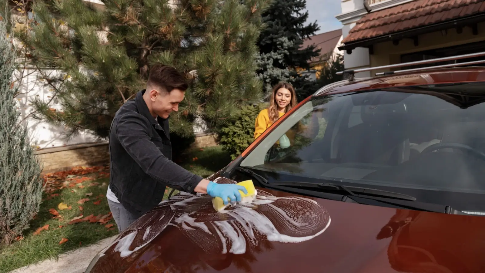 Chrysler sedan being washed with two-bucket method in a Michigan driveway during spring