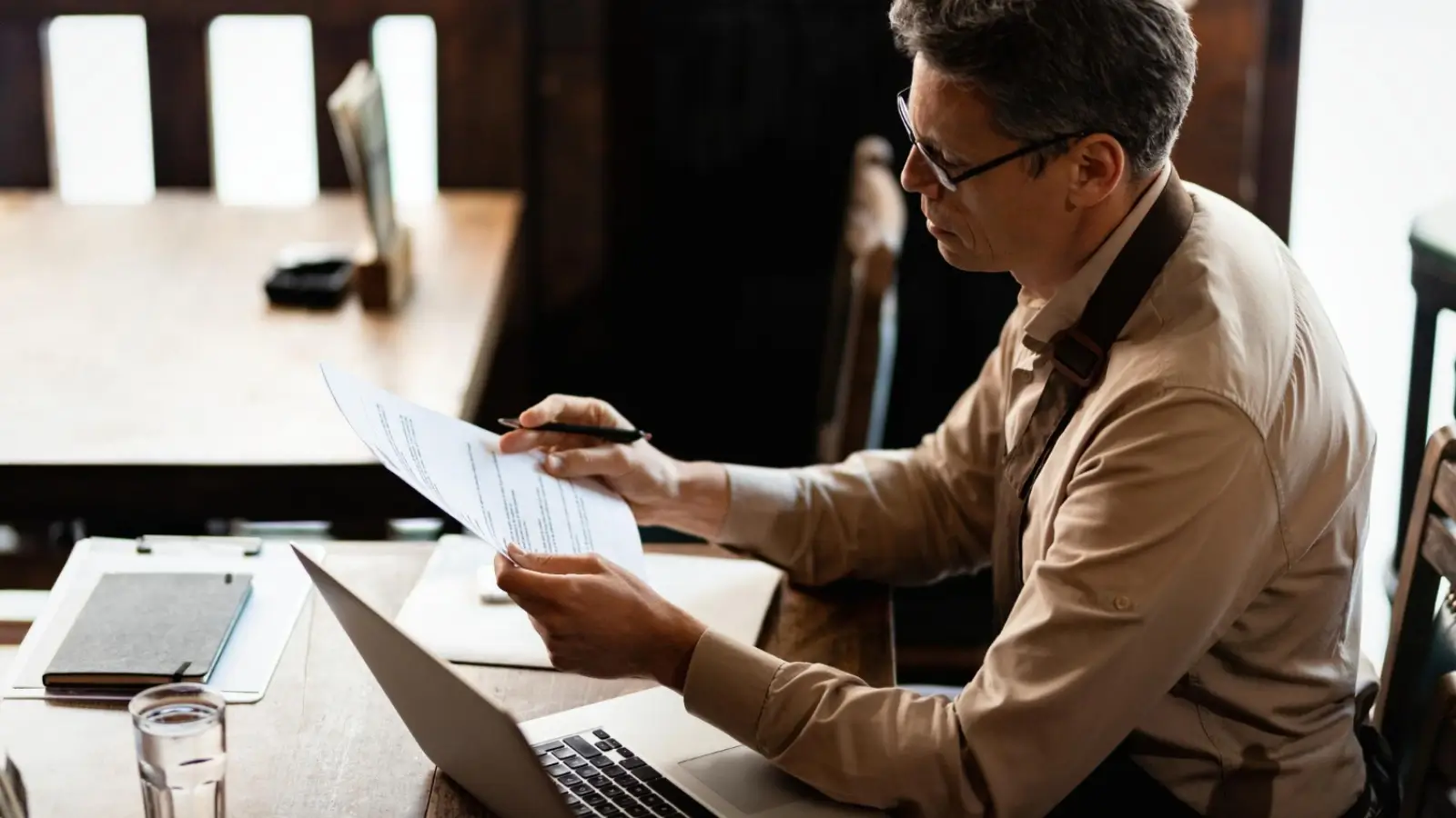 Entrepreneur reviewing financial documents at desk, planning for long-term business and personal security