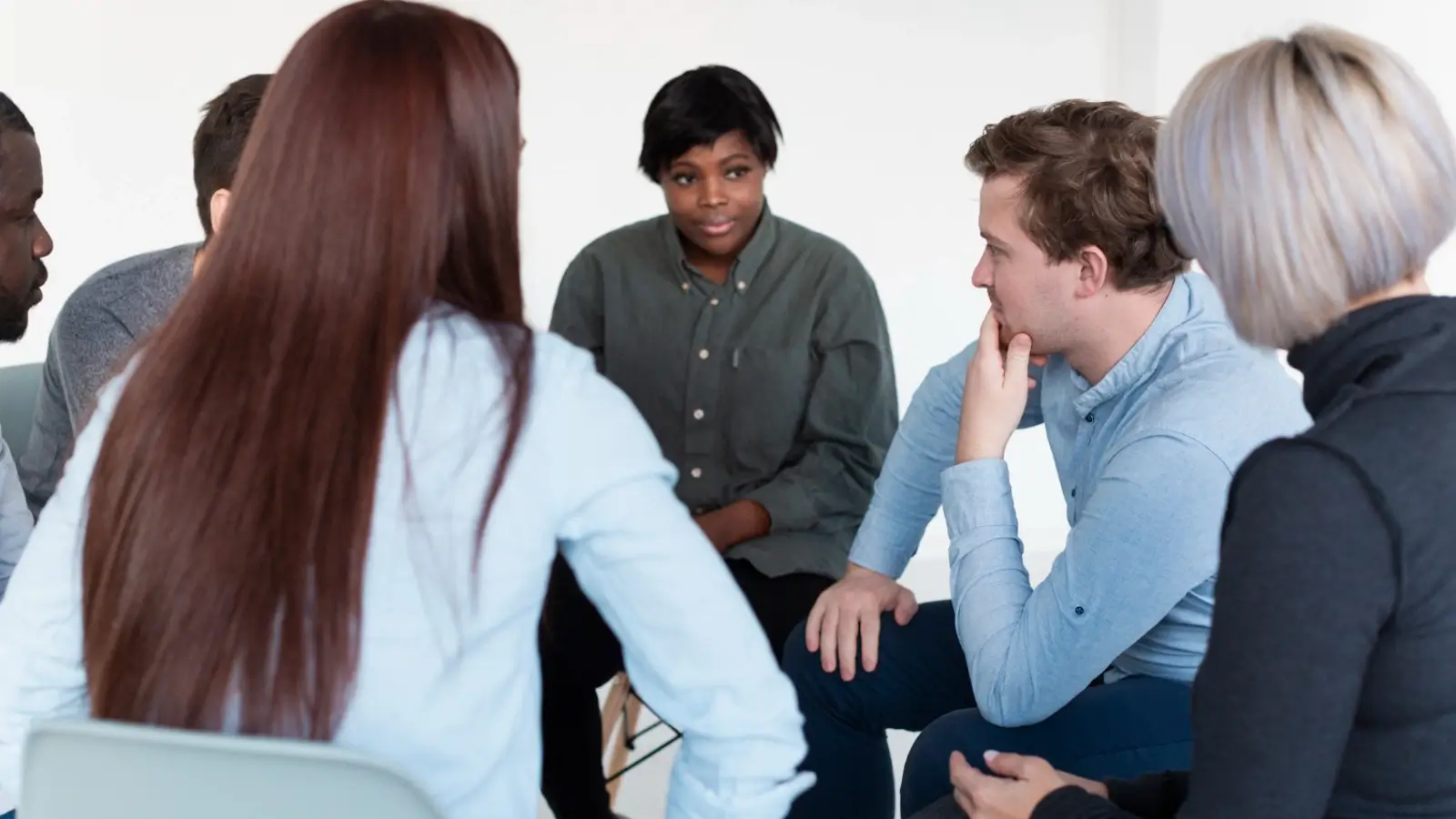 Group anger management session with counselor and participants engaged in discussion