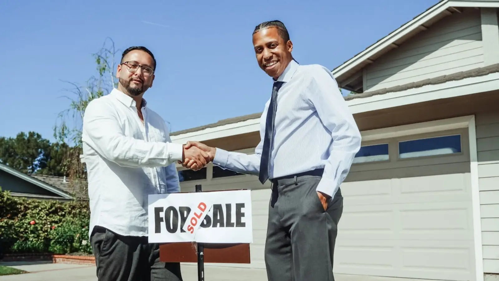 Homeowner shaking hands with cash buyer in front of house marked "Sold"