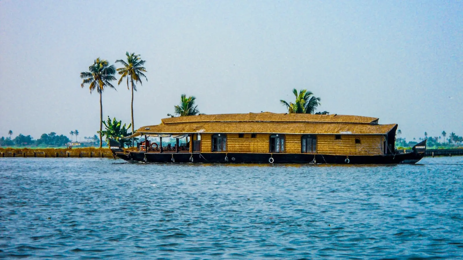 Houseboat cruising through the backwaters in Kerala surrounded by palm trees