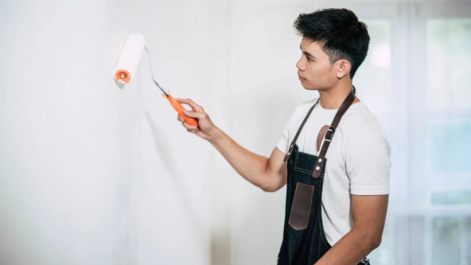 Impressions Painting professional adding a smooth coat of paint to a residential interior wall