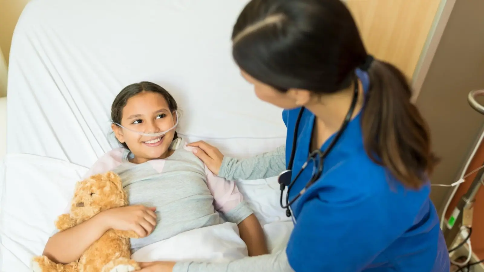 Nurse assisting a child with medical equipment at a pediatric extended care center