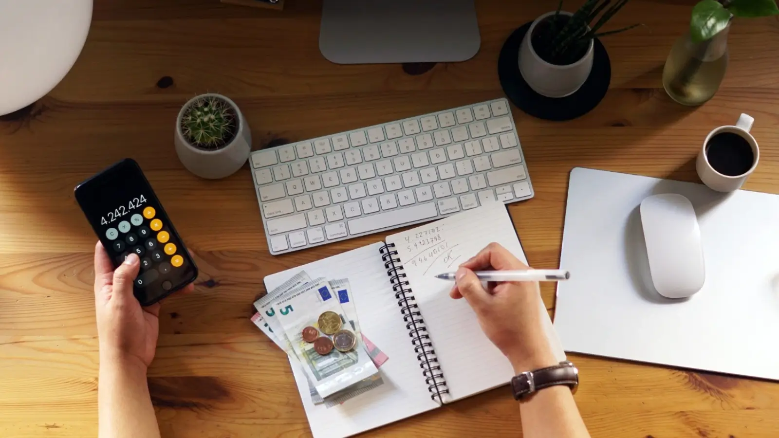Person reviewing budget and financial plans with calculator, notebook, and coffee on table