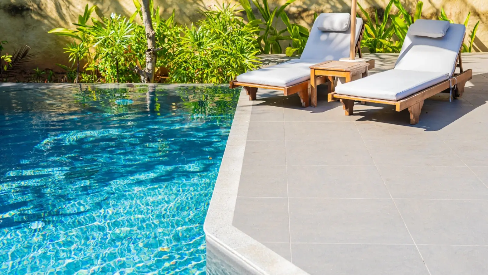 Resort-style backyard with natural stone pavers, greenery, and outdoor lounge furniture