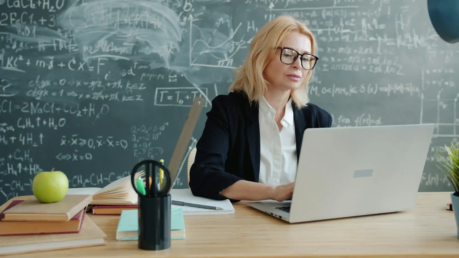 Teacher writing a college recommendation letter at a desk with student records