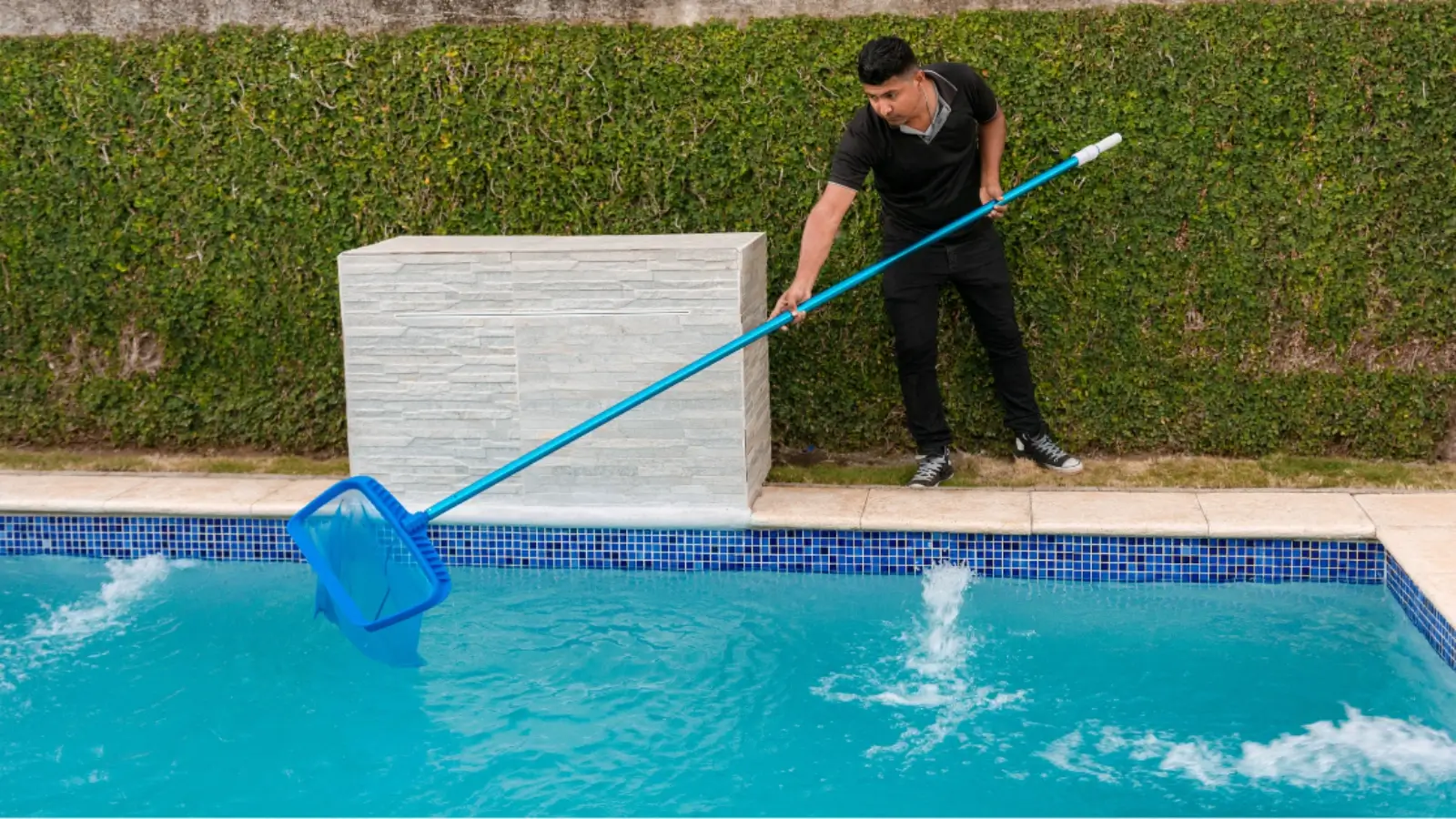 Technician performing professional pool cleaning in a residential backyard