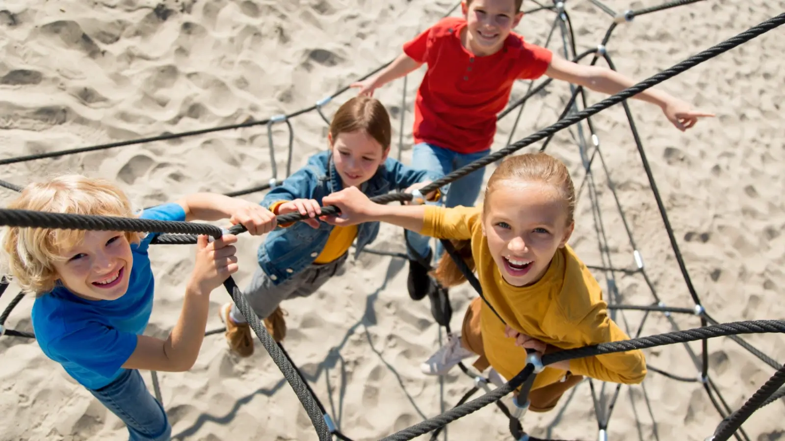 Children climbing a rope tower on a playground, developing strength and balance through active play.