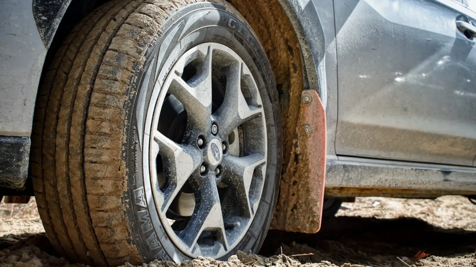 Close-up of a vehicle mud guard deflecting water and road debris during highway driving.