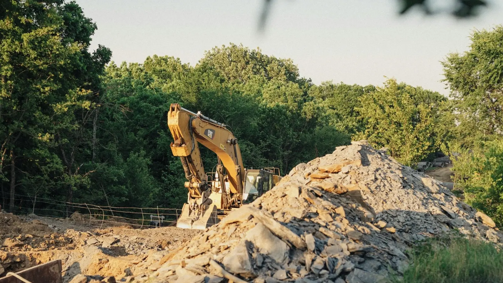 Excavator clearing trees and brush from a construction site
