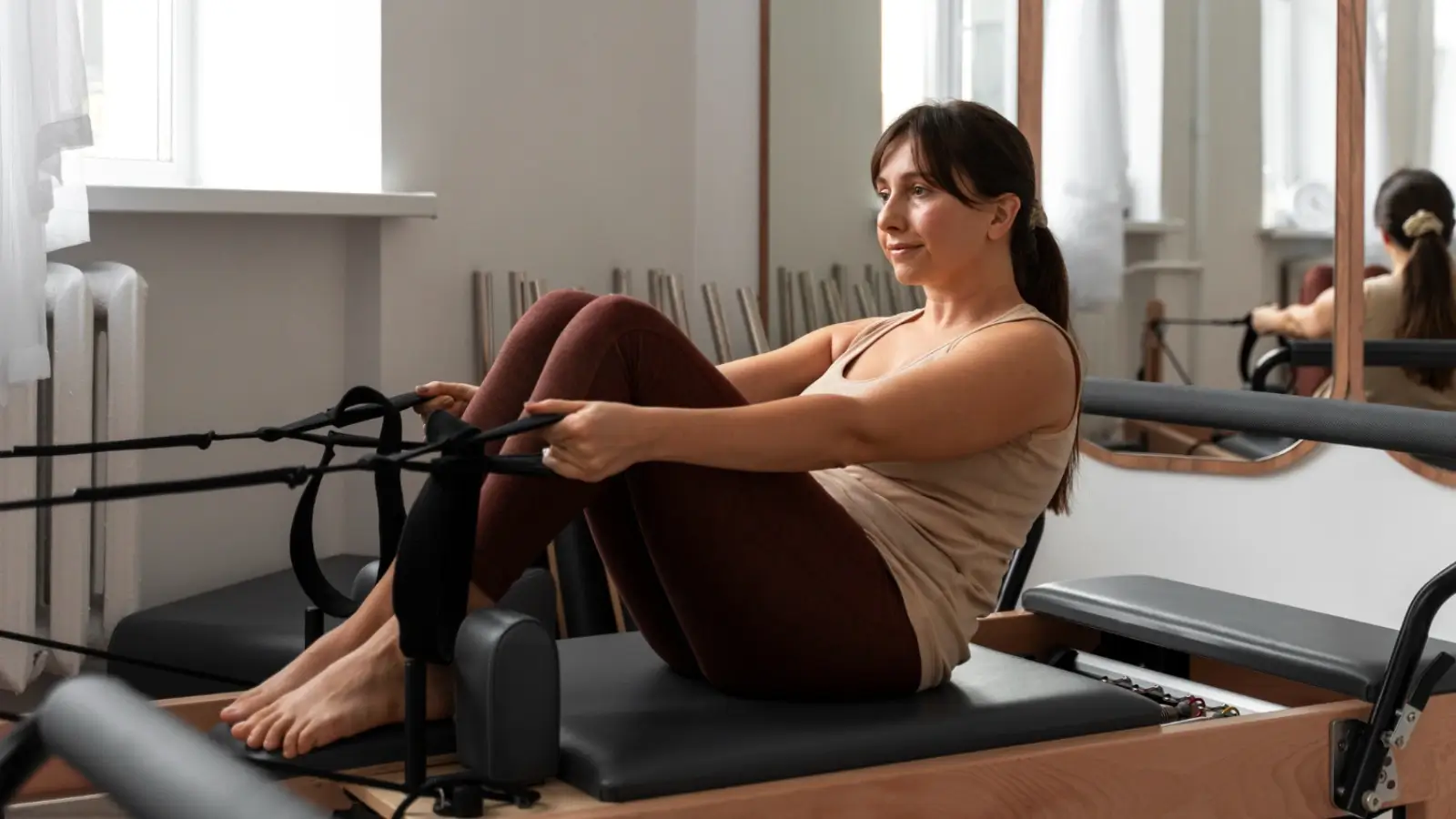 Person performing a core-strengthening workout on a reformer Pilates machine in a modern studio
