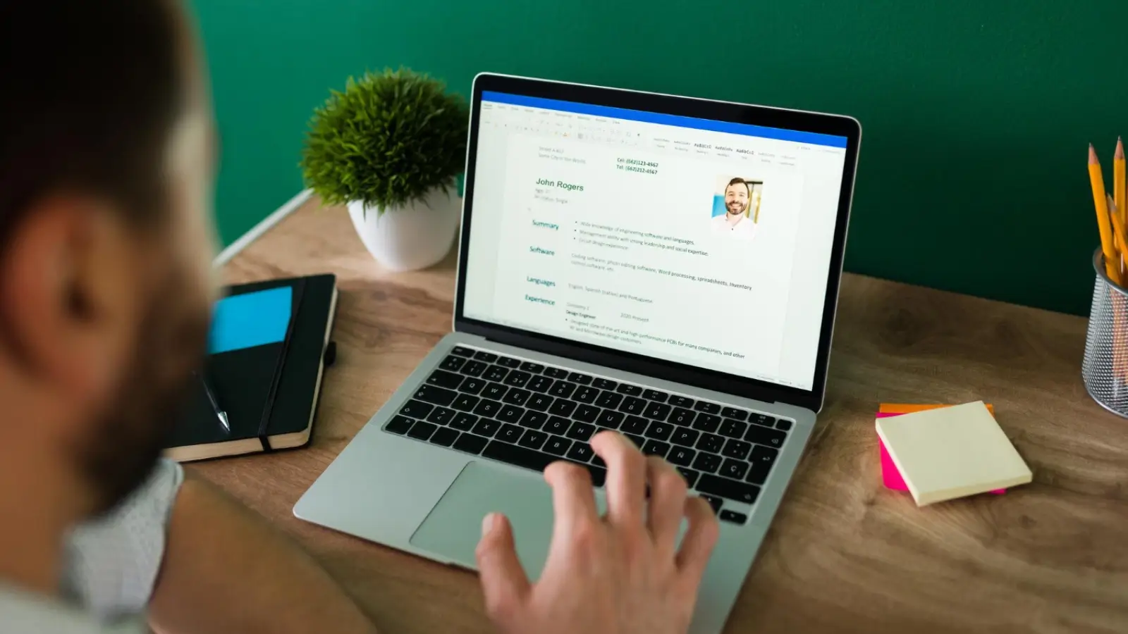 Job seeker updating resume on laptop with notes and professional template