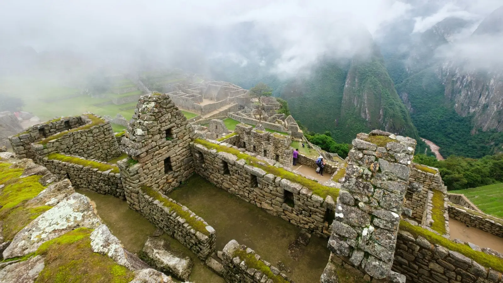 Traveler overlooking Machu Picchu ruins with misty Andes mountains in the background