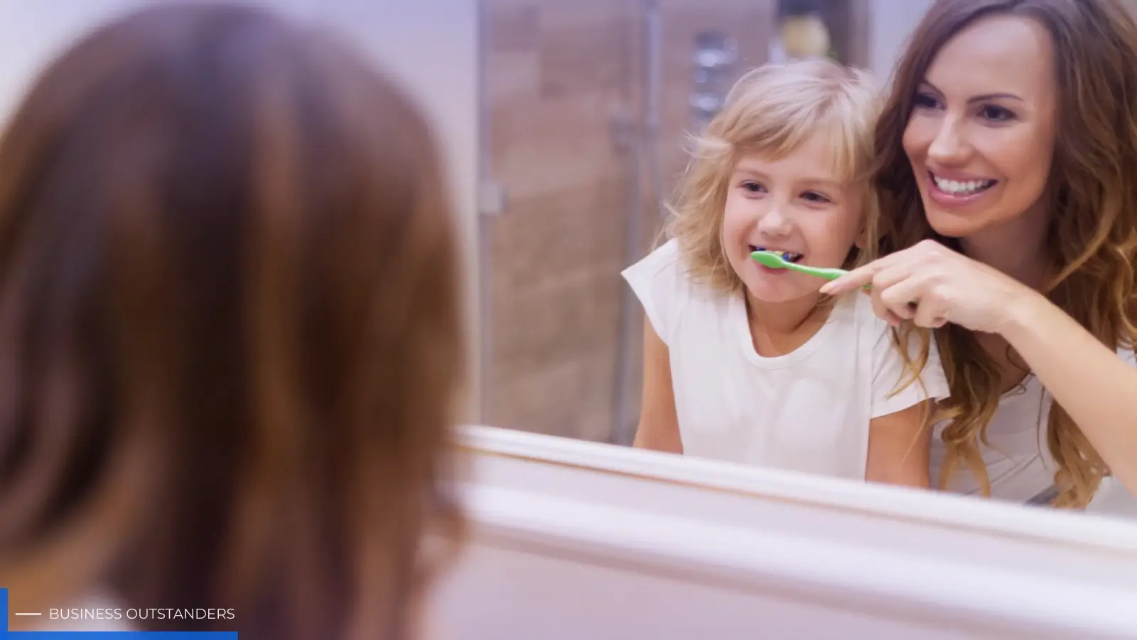 Parent helping young child brush teeth with colorful toothbrush in bathroom