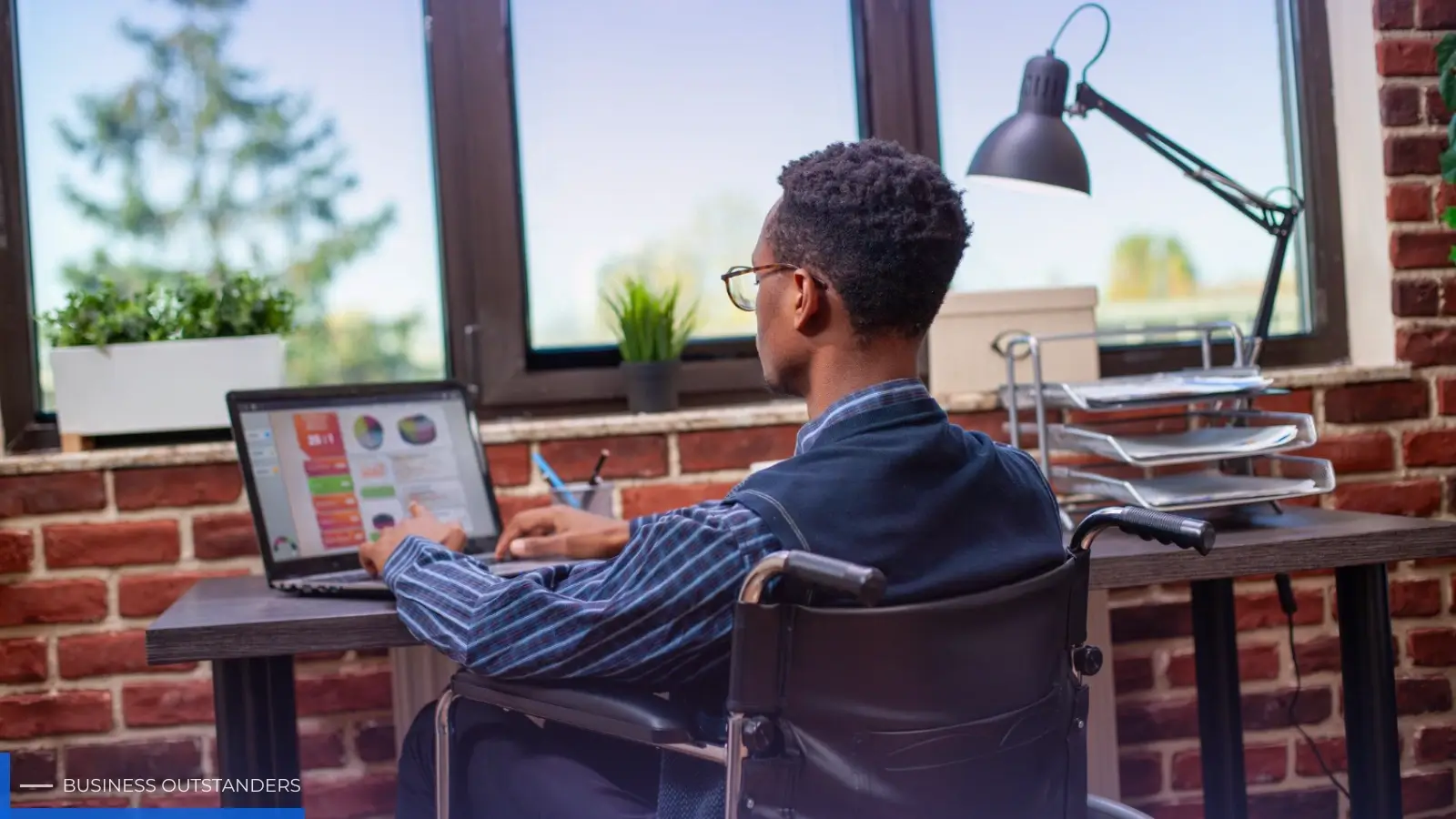 Person with disability using assistive technology to search for jobs on a laptop in an inclusive workspace