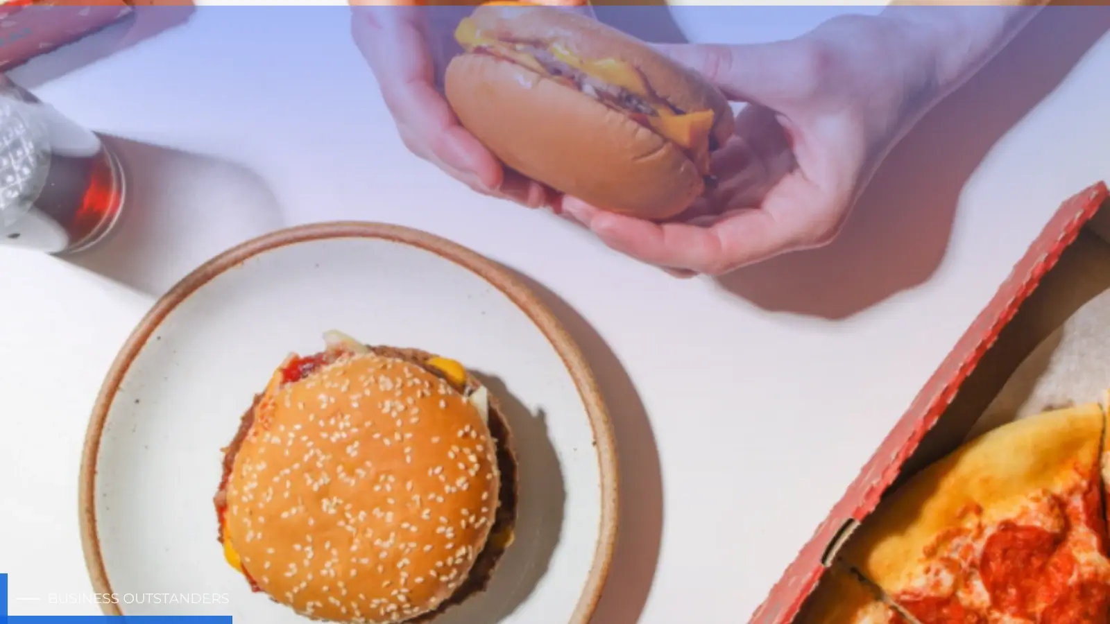Processed cheese slices being placed on a burger patty in a busy QSR kitchen assembly line