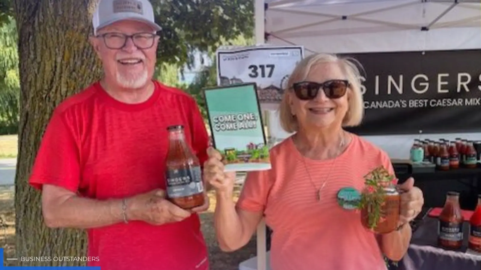 Barbara and Wayne Singer holding bottles of Singers Caesar Mix at a Canadian trade show booth